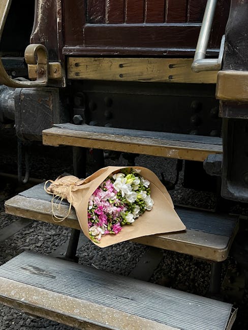 A floral bouquet from flowerdeliveryoldoakcommon.co.uk resting on a set of outdoor wooden train station steps. The bouquet features a mix of fresh flowers, including white roses, pink carnations, and 