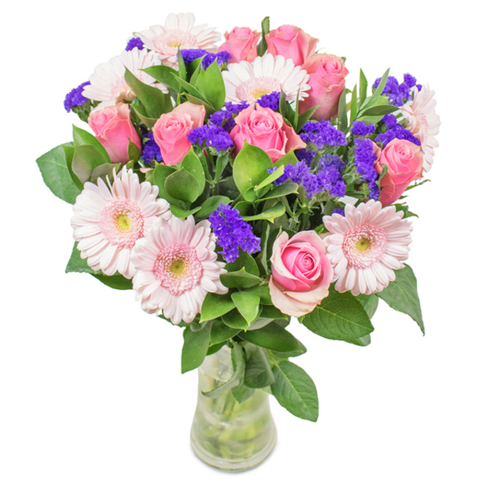 Against a clean, white background, this impressive floral ensemble from Old Oak Common's trusted florists commands attention with its expertly balanced colour and texture. Centered are approximately seven to nine roses, varying from softly furled buds to just-open pink spirals, radiating romance and sophistication. Swirled amongst them, five to seven pale gerbera daisies display their signature daisy heads and slightly pearlescent centers, adding a touch of gentle freshness. Accents of bold purple statice-reminiscent of wild summer blooms lining the paths near Little Wormwood Scrubs-are carefully interspersed, providing pockets of colour and visual interest. Deep, healthy foliage is layered at the base, its glossy leaves suggesting both abundance and the verdant beauty of Old Oak Common's natural scenery. Reset in a clear glass vase with visible stems and replenishing water, the arrangement signals care and day-of freshness. Here is a bouquet suited to birthdays, anniversaries, or simply as a joyful centrepiece for a living space in Old Oak Common, thoughtfully crafted to express celebration, gratitude, or affection and embodying the local florist's keen eye for detail.