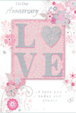 This anniversary card feels like a gentle nod to enduring romance, designed with the same sensitivity a local Old Oak Common florist brings to a long-awaited anniversary bouquet. At the heart of the composition sits the word LOVE, formed in softly raised glitter letters that shimmer as the card is tilted. Each letter is delicately dusted with fine silver sparkles, but the O stands out as a radiant heart shape, filled with denser silver texture so it gleams like a central bloom in a carefully composed arrangement. This motif rests against a blush-pink panel that gradually softens at the edges into a mist of pearly white and cool grey, suggesting a soft, ambient glow similar to dusk light over the nearby railway yard. Radiating outwards, clusters of delicate flowers unfurl in shades of blush, mauve, and pale ivory, painted with a translucent, watercolour softness that allows the background to peek through. The blooms, though stylised, evoke roses and garden blossoms arranged loosely, as though they might have been gathered from a small urban garden by Wormwood Scrubs. Fine lines describe curling stems and trailing vines, creating a sense of gentle movement around the central heart. Tiny flourishes-petals adrift, whimsical swirls, and almost invisible butterflies-are scattered with care, adding a hint of playfulness without disrupting the card's tranquil mood. Certain petals and curves are highlighted with subtle silver foil, echoing the glint of early morning dew on fresh foliage. The phrases On Our Anniversary and I love you today and always appear in a soft, flowing script, harmonising perfectly with the curves of the design. Overall, the card conveys a quiet, heartfelt celebration of shared years together, much like an elegant anniversary bouquet delivered across Old Oak Common.